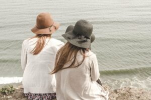 Par de amigas con sombreros sentadas en la playa