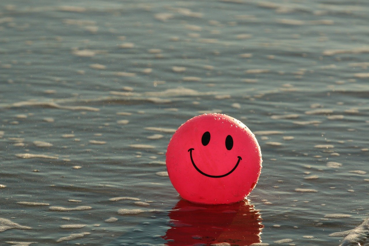 Pelota roja con cara feliz en el agua